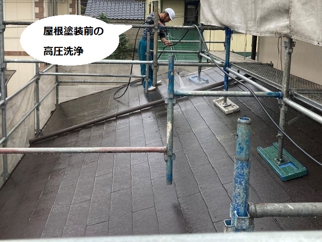 小雨の中で屋根の高圧洗浄を行う塗装職人
