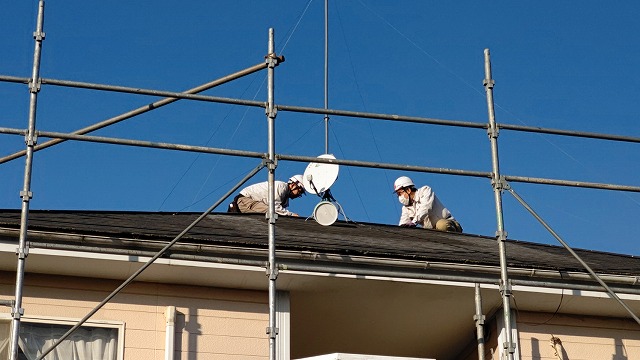 地上から撮影した屋根で作業する二名のスタッフ