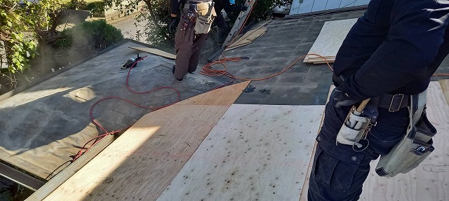 古い防水シートの上から12㎜の構造用合板を施工する職人