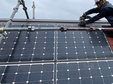 急勾配屋根で太陽光パネルを撤去する作業員