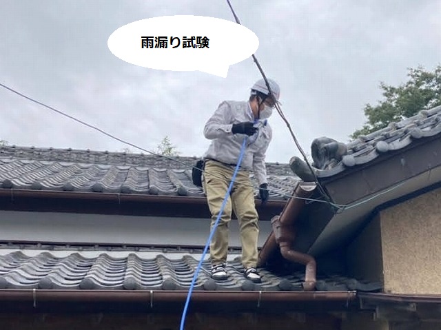 屋根に登り散水をして雨漏り試験を行うスタッフ