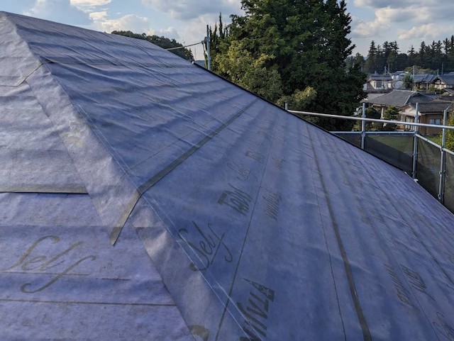紫の粘着式防水紙を屋根に敷設