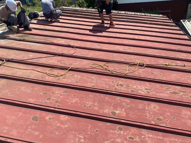 既存のトタン屋根を解体する職人