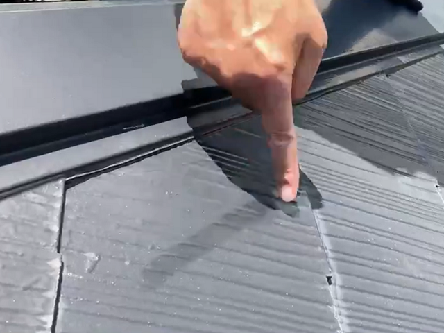 劣化したスレート屋根を指で擦る