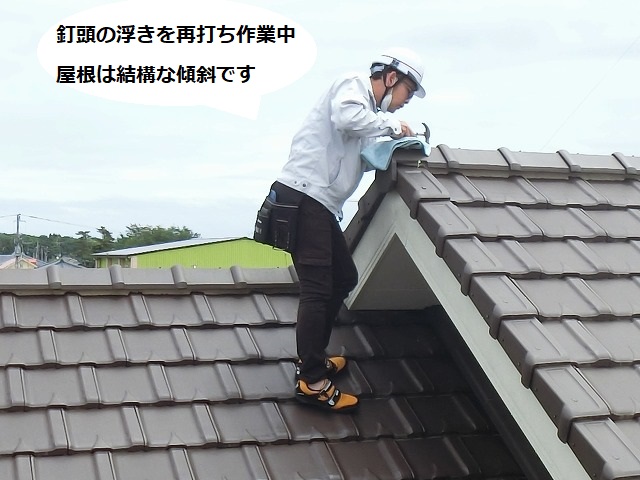 屋根の最も高い部分にある棟の浮き釘を打ち込む職人