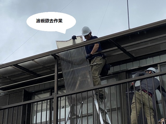 風に煽られながら2階のテラス波板を撤去する職人