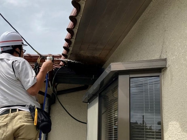 雨漏りの原因特定の為、上屋根と差し掛け屋根の間に散水を開始するスタッフ