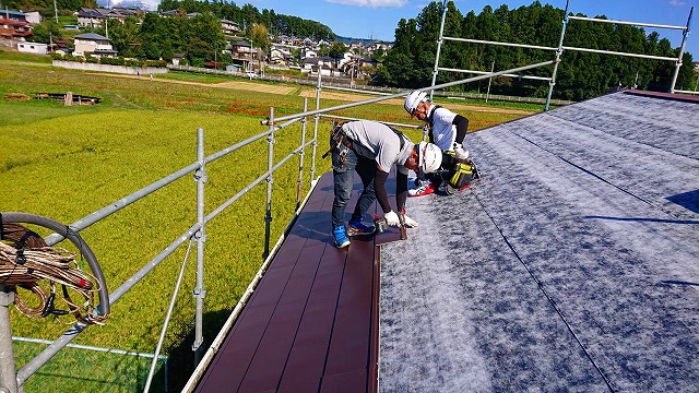 パミール屋根に金属屋根を施工中の二人の職人